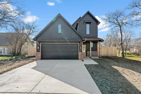 View of front of property with driveway, brick siding, and fence