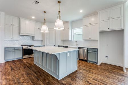 Kitchen featuring tasteful backsplash, stainless steel appliances, pendant lighting, a center island, and dark hardwood / wood-style flooring