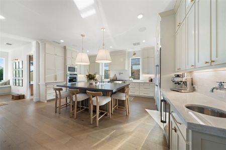 Kitchen featuring a center island, backsplash, sink, appliances with stainless steel finishes, and decorative light fixtures