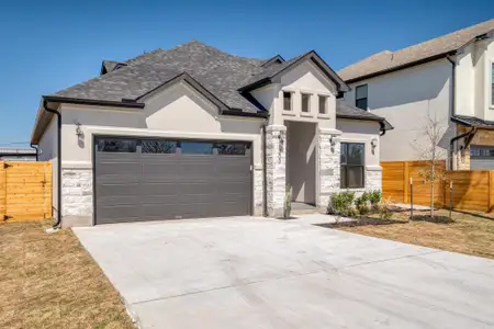 View of front of home featuring stone siding, stucco siding, a garage, and fence