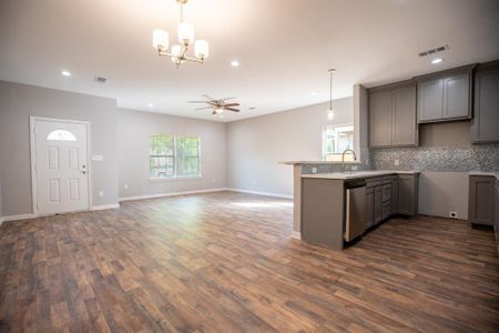 Kitchen with tasteful backsplash, dark wood-type flooring, ceiling fan with notable chandelier, gray cabinets, and decorative light fixtures