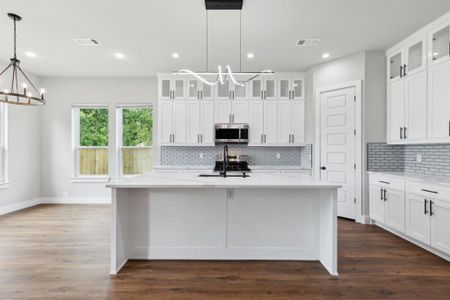 Kitchen featuring decorative light fixtures, appliances with stainless steel finishes, a chandelier, and a kitchen island with sink