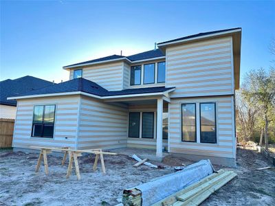 Back view. Covered patio and spacious backyard nestled on a corner lot.