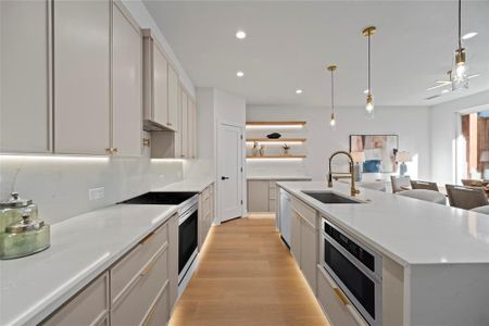 Kitchen featuring a kitchen island with sink, stainless steel appliances, sink, pendant lighting, and light hardwood / wood-style floors