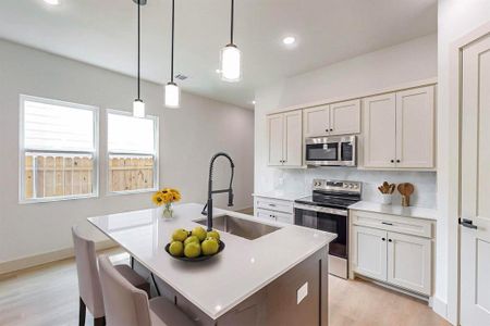 Kitchen with appliances with stainless steel finishes, white cabinetry, decorative light fixtures, and sink