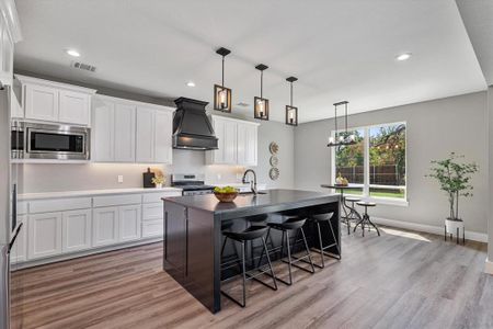 Kitchen with light hardwood / wood-style floors, stainless steel appliances, custom range hood, and white cabinetry