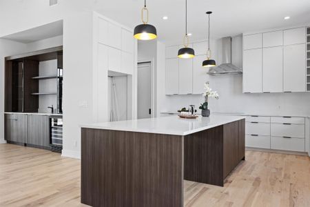 Kitchen with beverage cooler, white cabinetry, wall chimney range hood, modern cabinets, and light wood-type flooring