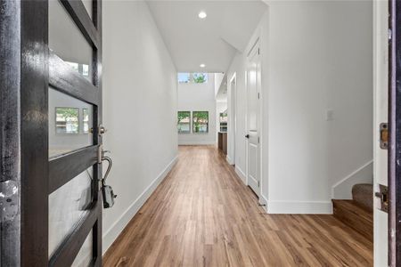 Corridor with a towering ceiling, plenty of natural light, and light wood-type flooring