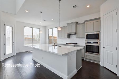 Kitchen with decorative backsplash, sink, a center island with sink, appliances with stainless steel finishes, and dark wood-type flooring