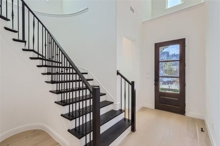 Entryway with light hardwood / wood-style floors and a towering ceiling