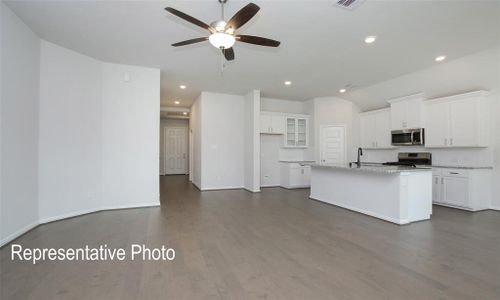 Kitchen with white cabinets, a center island with sink, dark wood-type flooring, appliances with stainless steel finishes, and light stone countertops