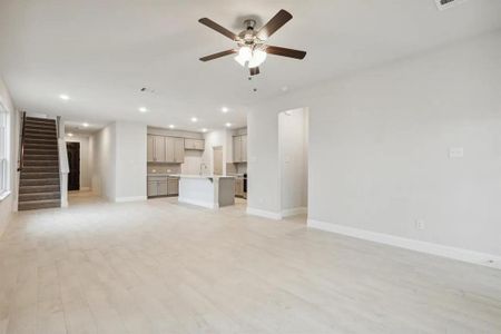 Unfurnished living room with ceiling fan, light wood-type flooring, and sink