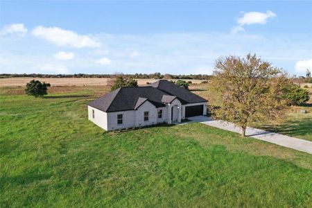 View of front facade with a rural view, a front yard, and a garage