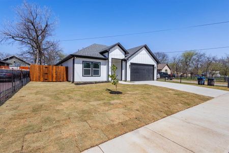 Modern inspired farmhouse featuring an attached garage, concrete driveway, roof with shingles, and fence