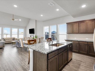 Kitchen featuring light wood-type flooring, light stone countertops, sink, and a kitchen island with sink