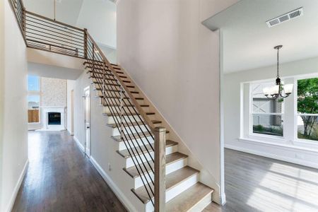 Stairway with a fireplace, hardwood / wood-style flooring, a towering ceiling, and a chandelier