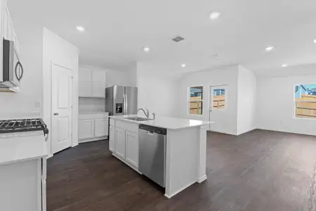 Kitchen featuring stainless steel appliances, dark wood-style flooring, a sink, white cabinetry, and an island with sink