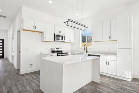 Kitchen with visible vents, appliances with stainless steel finishes, a center island, white cabinetry, and a sink