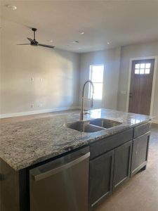 Kitchen with stainless steel dishwasher, stone counters, and sink