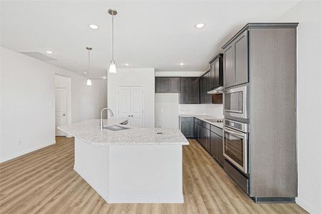 Kitchen featuring a kitchen island with sink, sink, decorative backsplash, appliances with stainless steel finishes, and decorative light fixtures