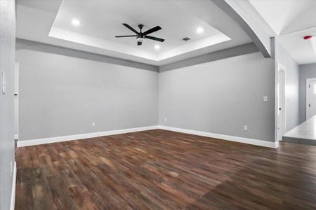 Empty room featuring dark hardwood / wood-style floors, a raised ceiling, and ceiling fan