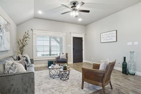 Living room featuring ceiling fan, wood-type flooring, and vaulted ceiling