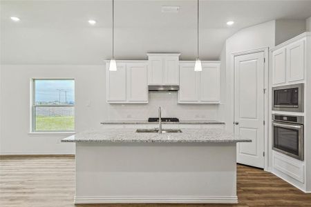 Kitchen featuring white cabinetry, stainless steel appliances, hardwood / wood-style flooring, decorative light fixtures, and tasteful backsplash