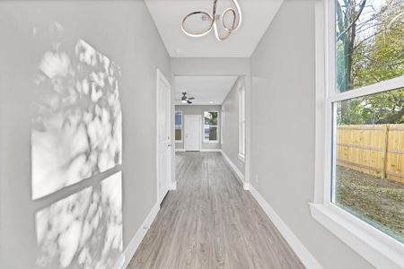 Hallway with hardwood / wood-style floors, an inviting chandelier, and a wealth of natural light