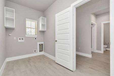 A perfect blend of functionality and comfort. Capture the essence of easy living with a first-floor laundry room, thoughtfully equipped with shelving for effortless organization. Sample photo of completed home with similar floor plan. As-built interior colors and selections may vary.