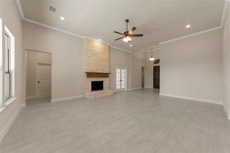 Unfurnished living room with a fireplace, ceiling fan, and crown molding