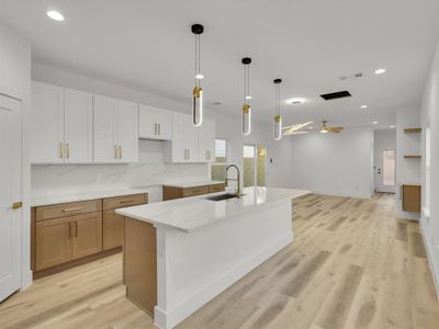 Kitchen featuring ceiling fan, a spacious island, sink, light hardwood / wood-style floors, and white cabinetry