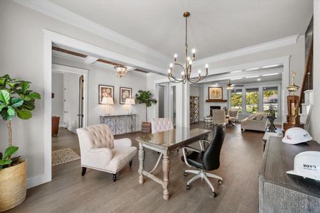 Dining room featuring ceiling fan with notable chandelier, a large fireplace, wood flooring, and ornamental molding all around!