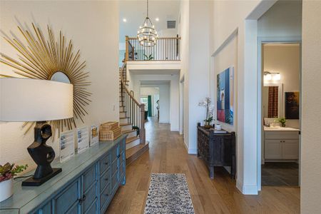 Foyer with a towering ceiling, a notable chandelier, hardwood / wood-style floors, and sink