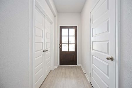 As you step inside, you'll be greeted by a grand foyer! This long hallway features smooth white walls and light hardwood flooring that creates a welcoming and spacious ambiance.