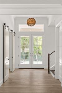 Foyer view showcasing the home's entry, featuring a double glass door, a decorative light fixture, and access to the office, stairwell, and storage closets.