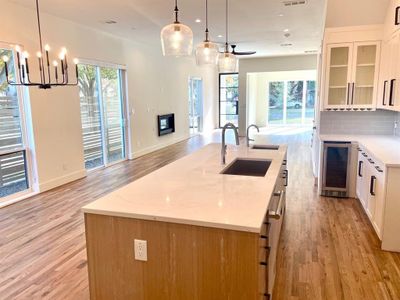 Kitchen featuring sink, an island with sink, light hardwood floors, and tasteful backsplash