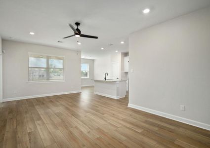 The spacious family room has a ceiling fan and plank flooring and is attached to the kitchen.