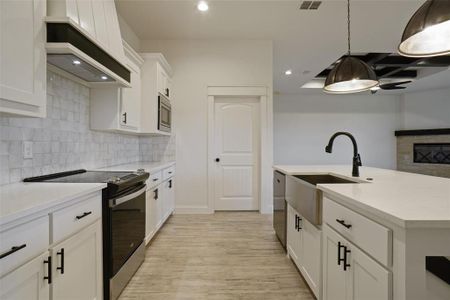 Kitchen featuring light hardwood / wood-style flooring, tasteful backsplash, white cabinets, premium range hood, and appliances with stainless steel finishes