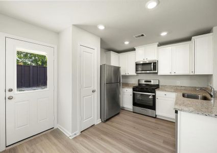 The kitchen has stainless steel appliances and plank flooring.