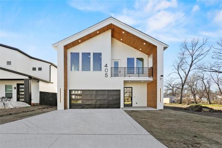 Modern home featuring driveway, an attached garage, a balcony, and stucco siding