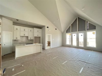 The open living and kitchen space unfolds seamlessly, characterized by an abundance of natural light pouring through expansive windows. Clean lines and neutral tones dominate, with a spacious countertop.