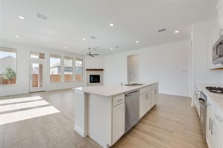 Kitchen featuring white cabinetry, sink, stainless steel appliances, light hardwood / wood-style flooring, and an island with sink