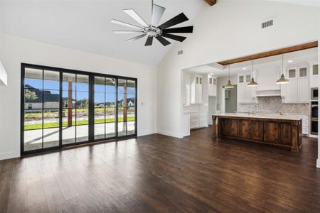 Unfurnished living room featuring beam ceiling, ceiling fan, sink, dark wood-type flooring, and high vaulted ceiling