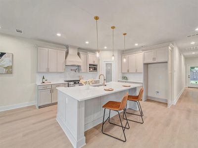 Kitchen with stainless steel appliances, custom exhaust hood, and white cabinets