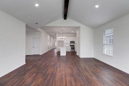 Unfurnished living room featuring a notable chandelier, vaulted ceiling with beams, and dark hardwood / wood-style floors