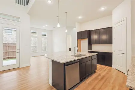 Kitchen with pendant lighting, a center island with sink, sink, stainless steel dishwasher, and light hardwood / wood-style floors