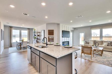 Kitchen featuring open floor plan, a kitchen island with sink, visible vents, and light stone countertops