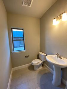 Powder bath off the entry with pedestal sink, window, and 12x24 tile