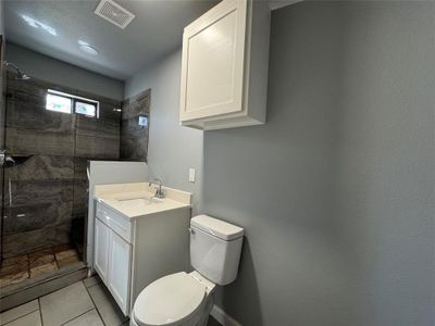 Bathroom featuring tiled shower, vanity, and toilet