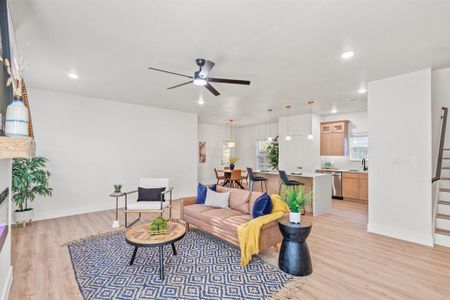 Living room with ceiling fan, sink, and light wood-type flooring